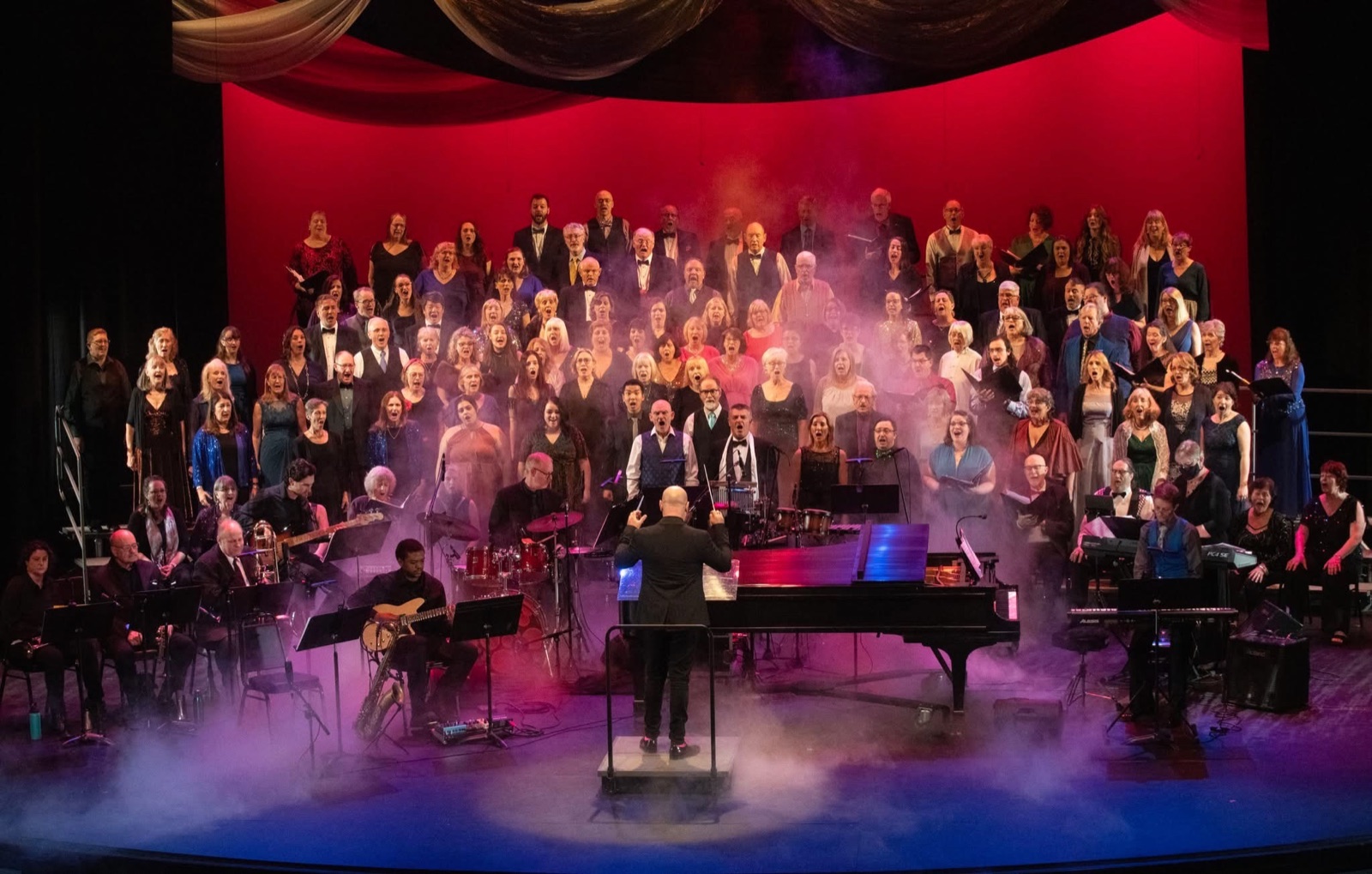 Next Stage Choir performing with musicians on a colourful concert stage
